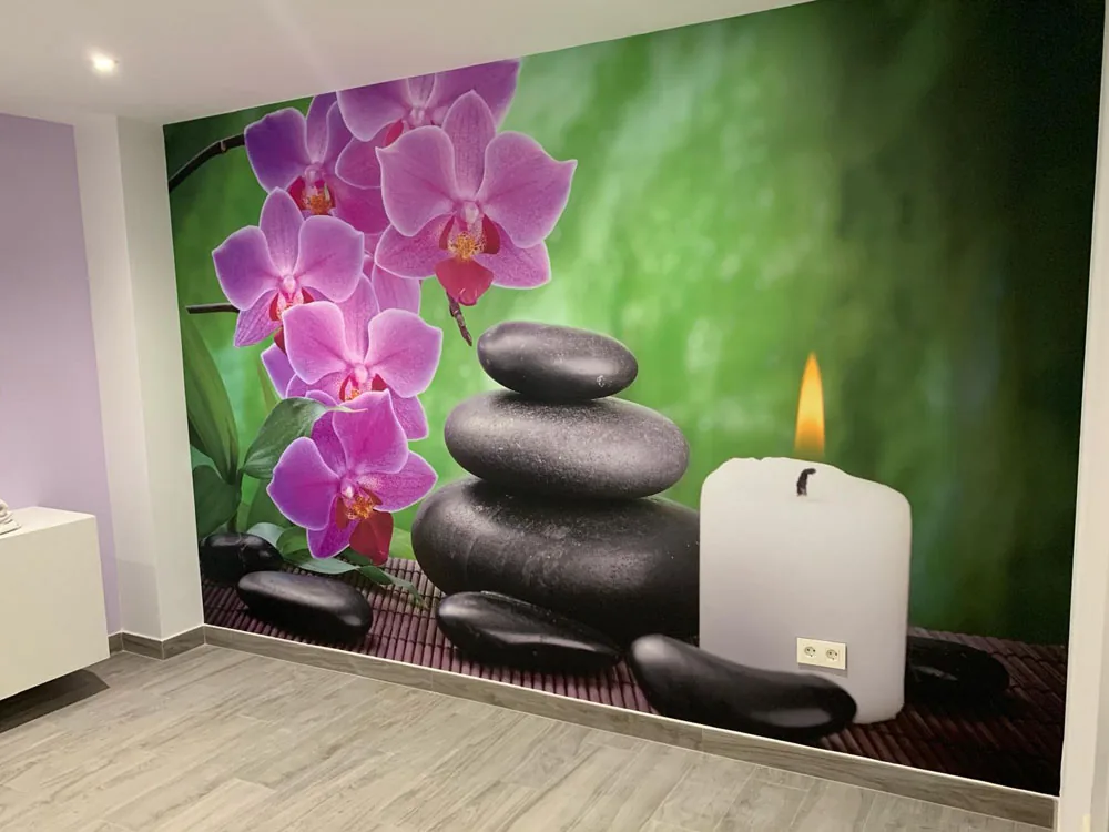 Vinilo decorativo de orquídeas, piedras y vela en pared de sala de masajes